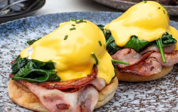Eggs benedict with ham, spinach and hollandaise on a muffin