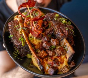 BBQ Banana Split dish with glazed meat and a bacon curl skewer
