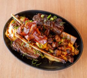 BBQ Banana Split dish with bone-in ribs and a bacon curl garnish