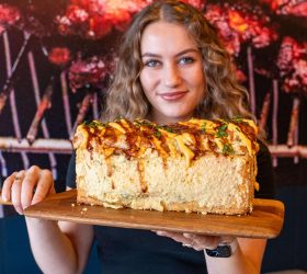 Person holding a large BBQ Brick loaf with sauce drizzle