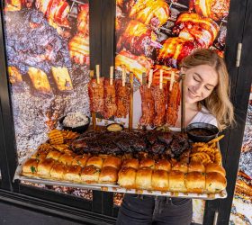 Guest beside a display of skewered Beef Rib Burnt Ends with bread rolls