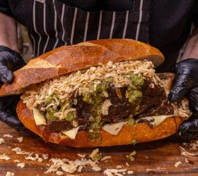 Chef holding the shredded beef roll with melted cheese and crispy shallots