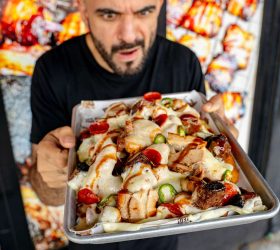 Chef holding a tray of Beast Mode Loaded Nuggets with cheese sauce and jalapenos