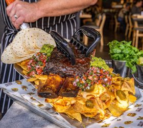 Chef holding the Shovelled Grizzly Nachos with bear claws and guacamole