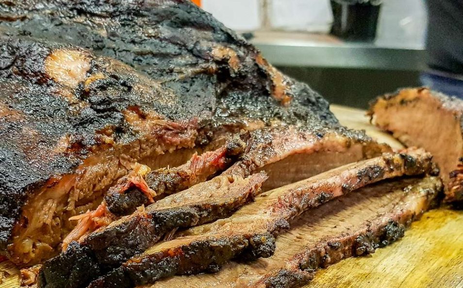 Sliced smoked beef brisket with a dark bark on a board