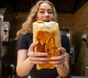 Guest holding the foil-wrapped Brisket Lasagna Burrito