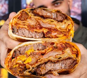 Guest holding two halves of the Brisket Lasagna Burrito showing pasta filling