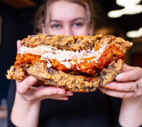 Guest holding the Chicken Fried Brisket Fried Chicken Sandwich with coleslaw