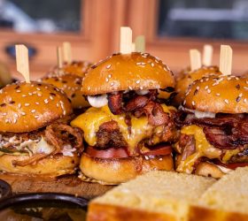 Loaded burger sliders with bacon and cheese on a board