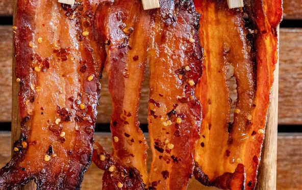 Candy bacon strips hanging from wooden pegs