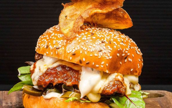 Fried chicken burger with bacon, cheese sauce and a chip garnish