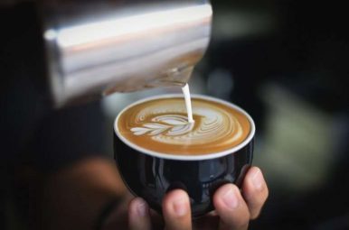 Barista pouring latte art into a coffee cup
