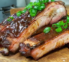 Sliced smoked pork ribs with a pink smoke ring and spring onion garnish