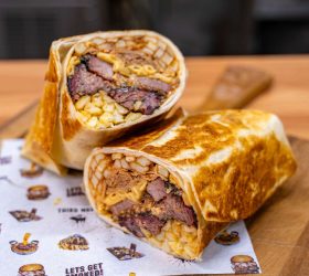 Everything Burrito halves on a wooden board showing brisket and mac and cheese