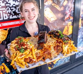 Staff member holding the Holy Fluck Parma loaded fries platter
