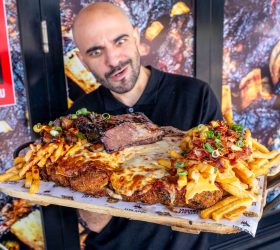 Chef holding the Holy Fluck Parma loaded with cheese sauce and chips