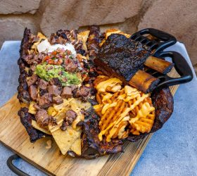 Hogzilla nacho platter with waffle fries and guacamole on a bear-claw board
