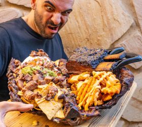 Guest holding the Hogzilla nacho board with bear-claw handles and waffle fries