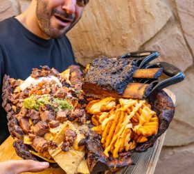Person holding the Hogzilla board loaded with meat, cheese and fries
