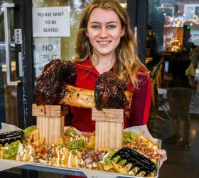 Guest holding the Odin's Dumbbell Nachos tray inside Third Wave BBQ