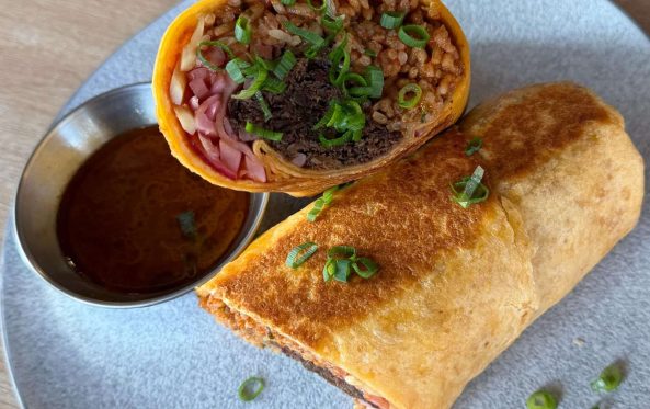 Beef wrap sliced in half with a side of dipping sauce
