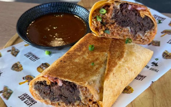 Beef wrap sliced in half on a board with dipping sauce