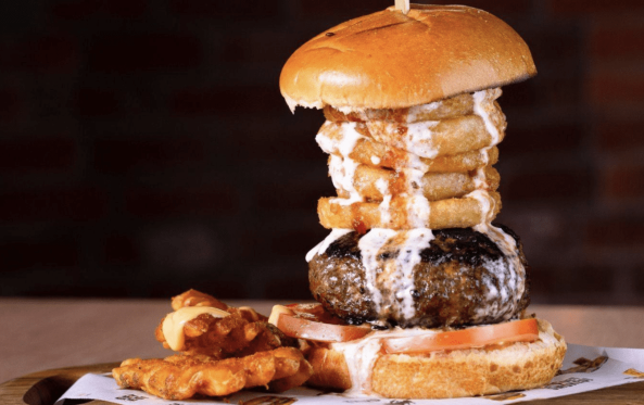 Jucy burger topped with a skewer of onion rings