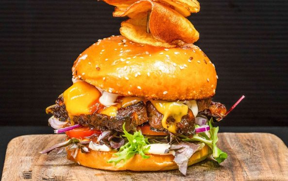 Lamb burger with melted cheese, tomato and a chip garnish