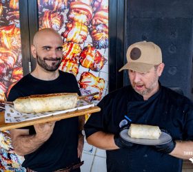 Two staff holding wrapped Long Horn Burritos at the entrance