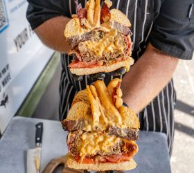 Chef holding two halves of the Mac Bomb on Steroids showing cheese filling