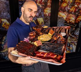 Chef holding the Meat Coma Platter loaded with ribs and brisket