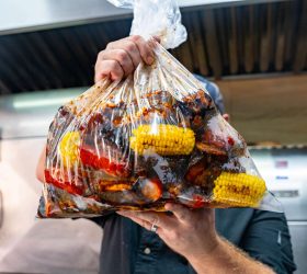 BBQ Meat Sack bag filled with ribs and corn cobs held up to camera