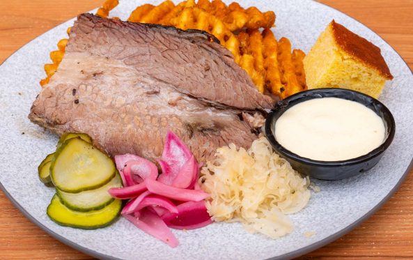 Sliced brisket with waffle fries, cornbread and pickles