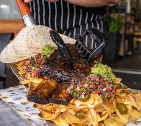 Grizzly Shovel Nachos tray with bear claws and pico de gallo, held by a chef