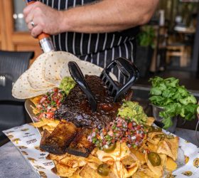 Chef holding the Grizzly Shovel Nachos with bear claws and guacamole