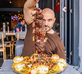 Guest pulling the Excalibur Ribs Platter skewer from a bed of rolls and garnish