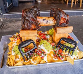 Odin's Dumbbell Nachos with rib bones styled as a barbell over loaded nachos