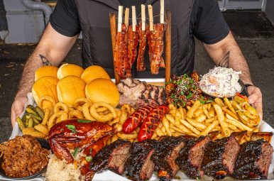 Large BBQ platter with ribs, brisket and sides held out