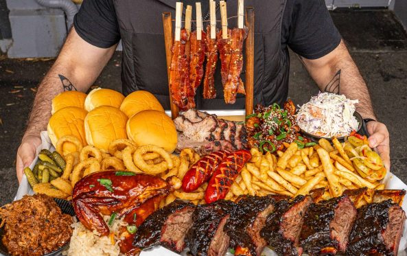 Large BBQ platter with ribs, brisket and sides held out