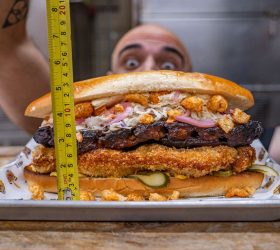 The Hog Father sandwich measured with a tape measure showing its height