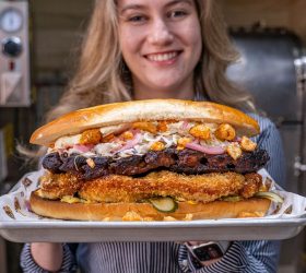 Person holding The Hog Father sandwich loaded with schnitzel and ribs