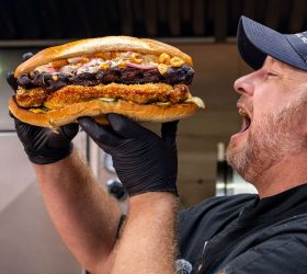 Chef biting into The Hog Father loaded sandwich