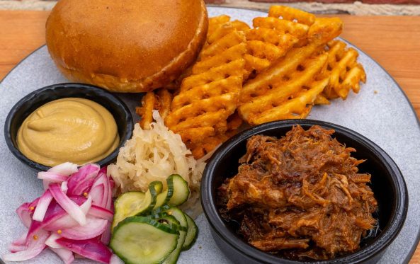 Pulled pork plate with a bun, waffle fries and pickles