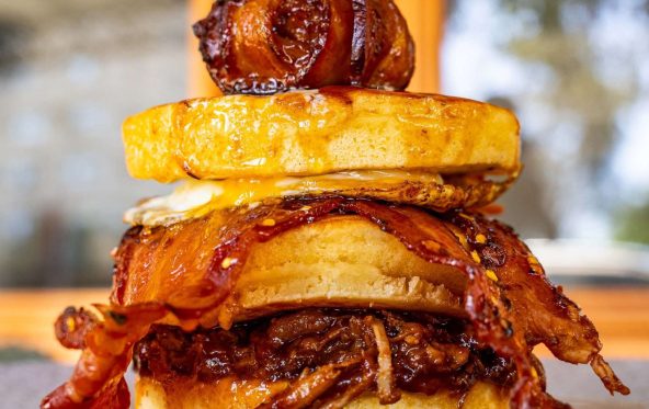Towering bacon and hash brown stack skewered on a plate