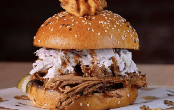 Pulled pork burger stacked with onion rings on a board