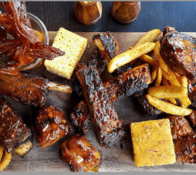 BBQ ribs with onion rings, fries and cornbread on a platter