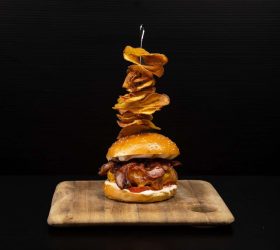 Royal burger stacked with onion rings on a board