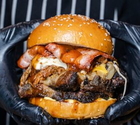 Oh Mamma burger loaded with bacon and cheese on the grill