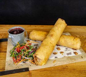 XXXL Spring Rolls with side salad and dipping sauce on a board