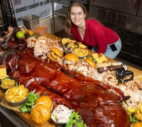 Whole Hog Degustation spread with a whole roasted pig, burgers and sides